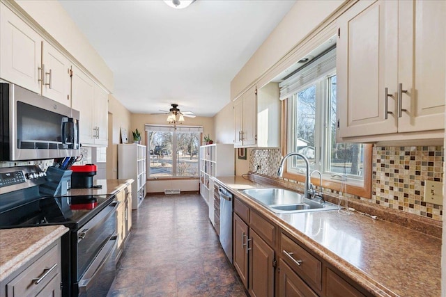 kitchen with backsplash, stainless steel appliances, light countertops, and a sink