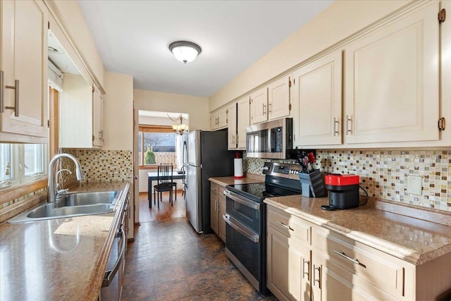 kitchen with backsplash, a chandelier, light countertops, appliances with stainless steel finishes, and a sink