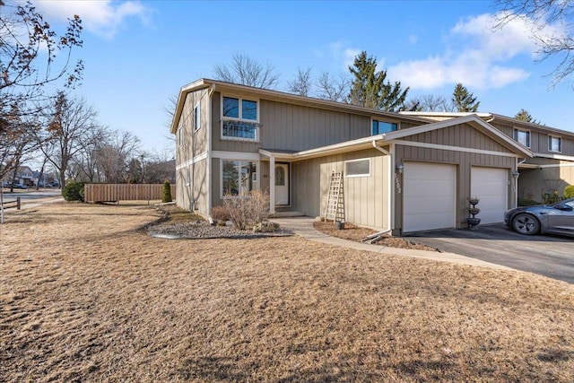 view of front of house featuring driveway, a garage, and fence