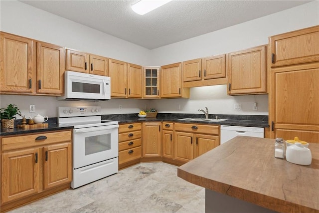 kitchen featuring sink, white appliances, and a textured ceiling