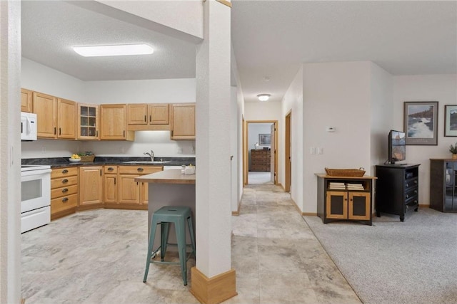 kitchen featuring a kitchen bar, light brown cabinetry, sink, light carpet, and white appliances