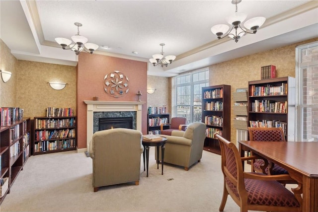 living room featuring a raised ceiling, a premium fireplace, light colored carpet, and an inviting chandelier