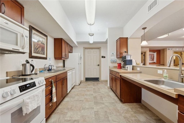 kitchen featuring sink, pendant lighting, and white appliances