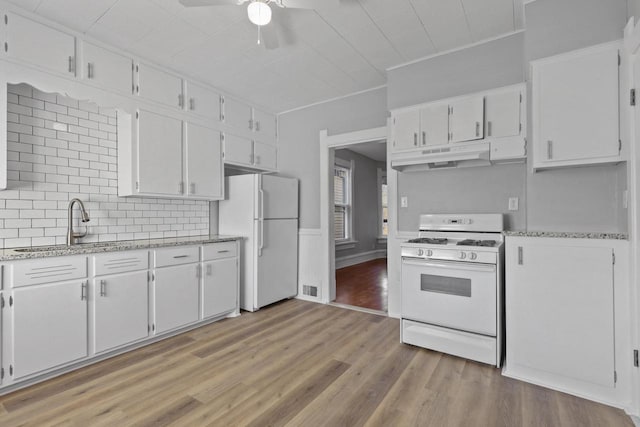 kitchen with white appliances, light hardwood / wood-style flooring, ceiling fan, white cabinetry, and tasteful backsplash