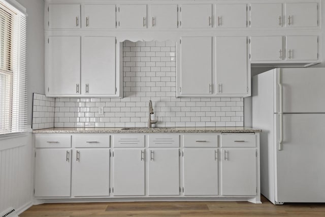 kitchen with white refrigerator and white cabinetry