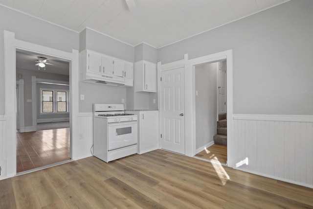 kitchen featuring light wood-type flooring, ceiling fan, white gas stove, and white cabinets