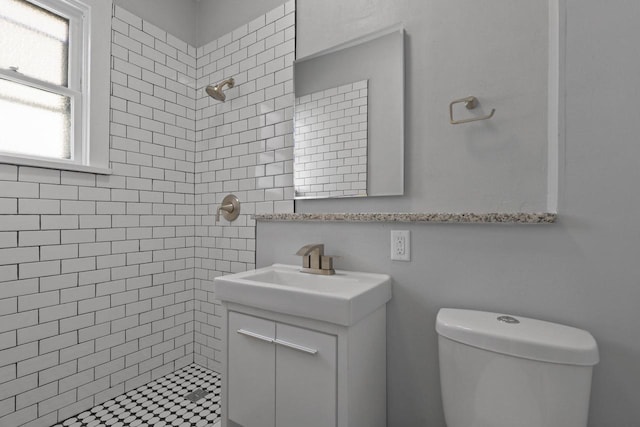 bathroom with vanity, toilet, and tiled shower