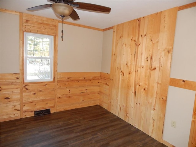 unfurnished room with ceiling fan, dark hardwood / wood-style floors, and wooden walls