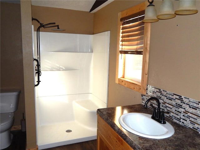 bathroom featuring backsplash, vanity, toilet, and a shower