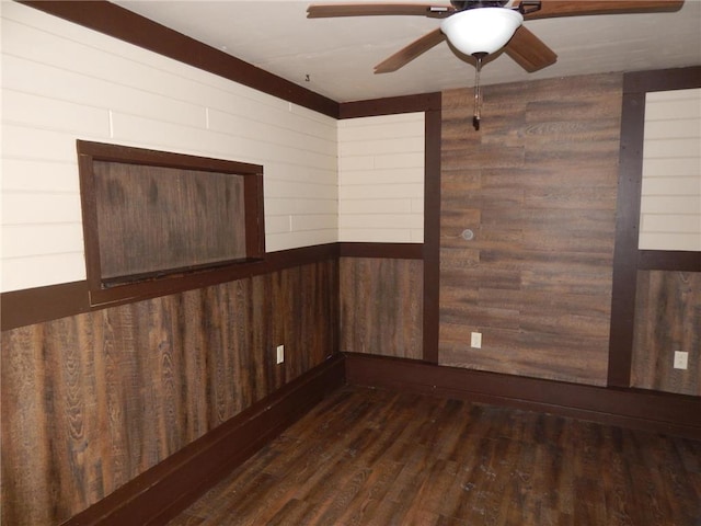 spare room with dark hardwood / wood-style floors, ceiling fan, and wood walls