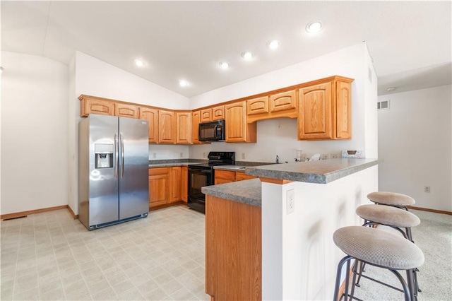 kitchen featuring kitchen peninsula, vaulted ceiling, a breakfast bar area, and black appliances