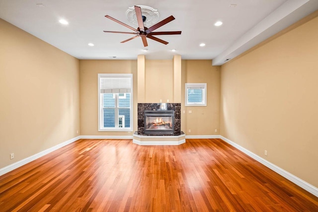 unfurnished living room featuring hardwood / wood-style flooring, a fireplace, and ceiling fan