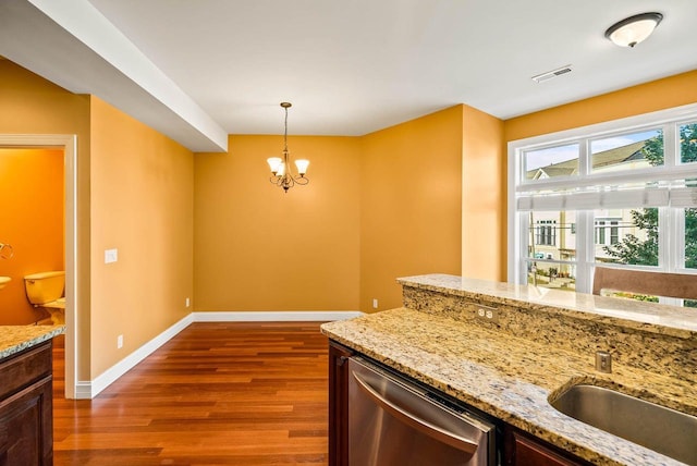 kitchen featuring hanging light fixtures, wood-type flooring, light stone countertops, and dishwasher