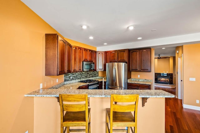 kitchen with light stone counters, a breakfast bar, kitchen peninsula, and appliances with stainless steel finishes