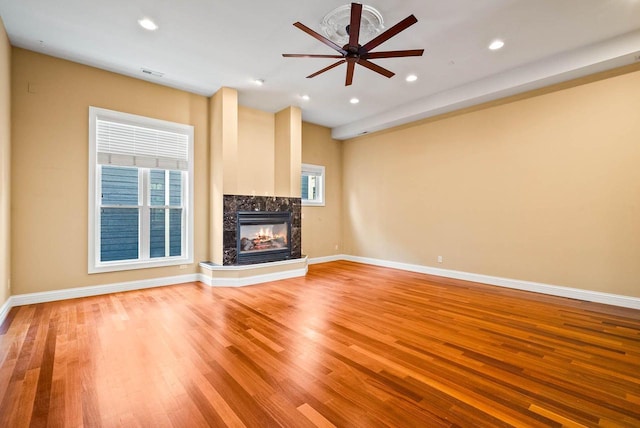 unfurnished living room with a premium fireplace, plenty of natural light, and wood-type flooring