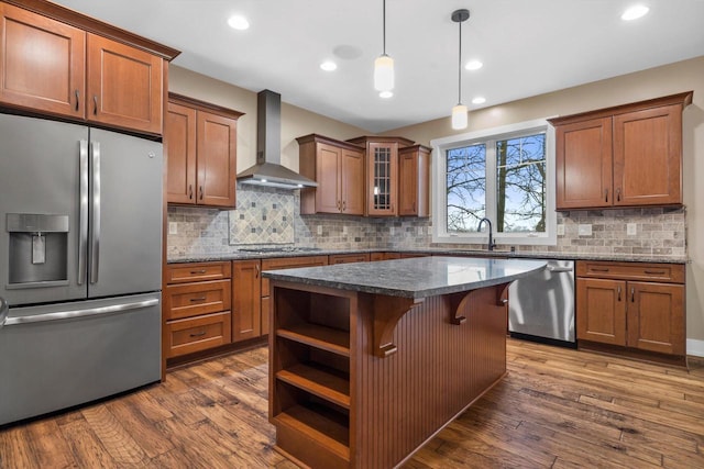 kitchen with appliances with stainless steel finishes, pendant lighting, a breakfast bar area, a center island, and wall chimney exhaust hood