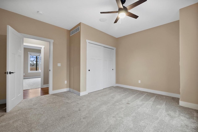 unfurnished bedroom with ceiling fan, light colored carpet, and a closet