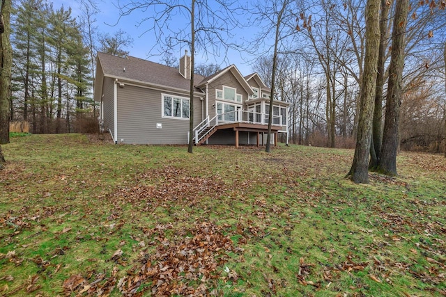 rear view of house with a wooden deck, a sunroom, and a yard