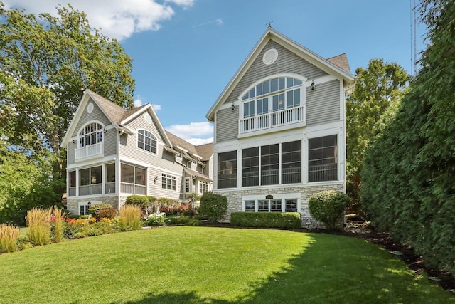 rear view of property with a sunroom and a lawn