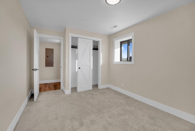 unfurnished bedroom featuring light carpet, electric panel, and a closet