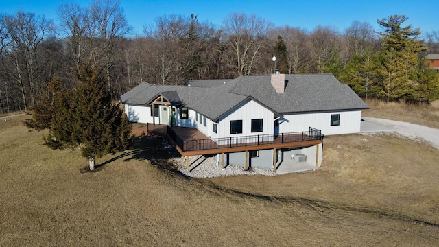 back of property with a deck and a lawn