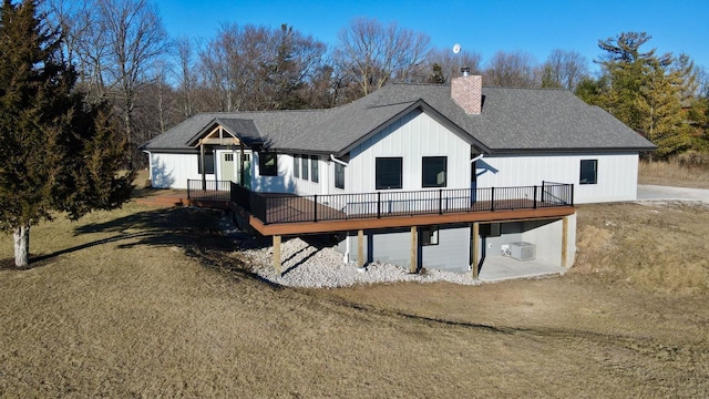 back of property featuring a wooden deck and a lawn