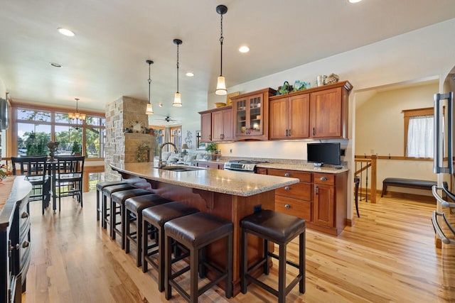 kitchen featuring a breakfast bar, stainless steel stove, sink, hanging light fixtures, and light hardwood / wood-style floors