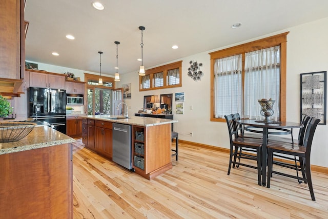 kitchen with sink, a breakfast bar, appliances with stainless steel finishes, hanging light fixtures, and a center island with sink