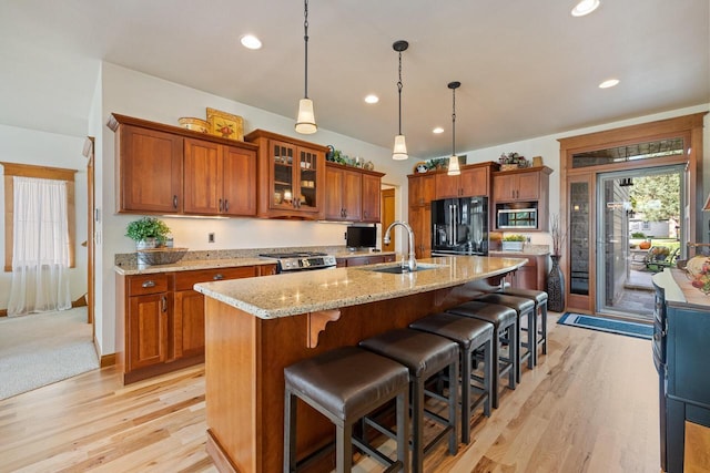 kitchen featuring pendant lighting, stainless steel appliances, a kitchen breakfast bar, and an island with sink