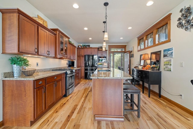 kitchen featuring appliances with stainless steel finishes, pendant lighting, an island with sink, sink, and a kitchen bar