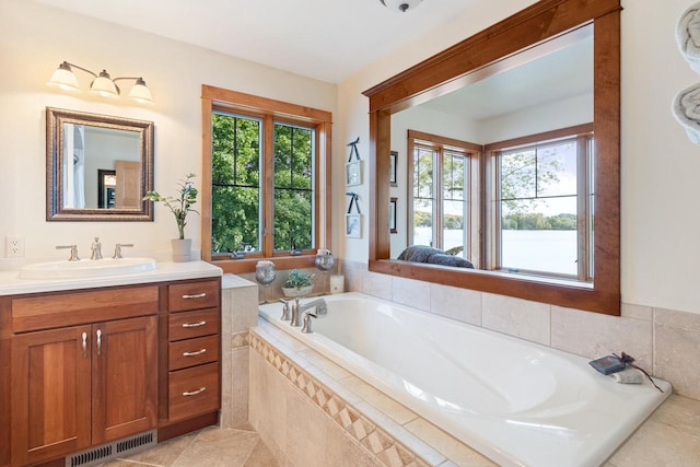 bathroom with vanity, a wealth of natural light, and tiled bath