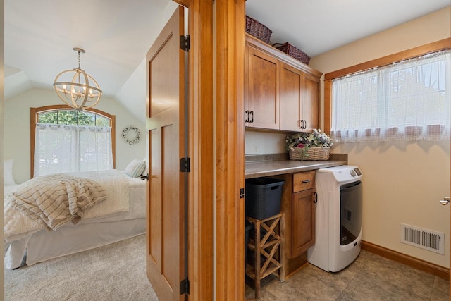 laundry room featuring light carpet, washer / dryer, cabinets, and a chandelier