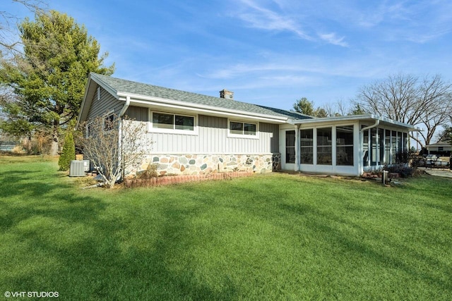 rear view of property featuring central AC, a sunroom, and a lawn