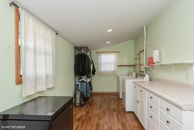 clothes washing area featuring cabinets, washing machine and clothes dryer, and dark wood-type flooring