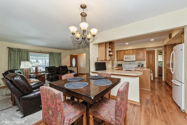 dining space with light hardwood / wood-style floors and a chandelier