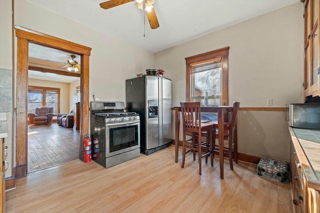 kitchen with ceiling fan, appliances with stainless steel finishes, tile countertops, and light hardwood / wood-style floors