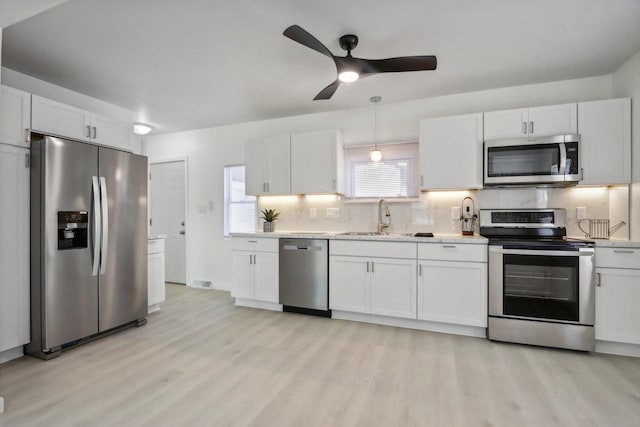 kitchen with sink, white cabinetry, backsplash, stainless steel appliances, and light hardwood / wood-style floors