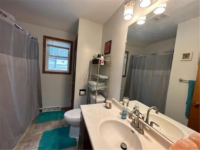 full bathroom featuring toilet, vanity, and visible vents