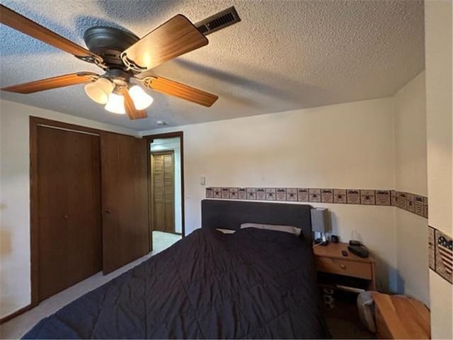 bedroom featuring a textured ceiling, a closet, visible vents, and a ceiling fan