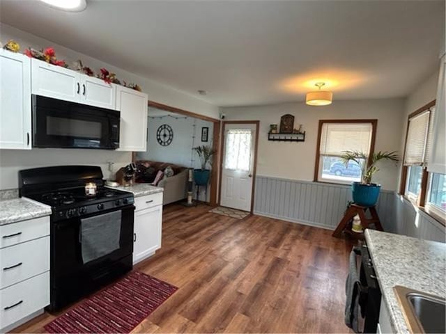 kitchen featuring black appliances, dark wood-style floors, white cabinets, and a wainscoted wall