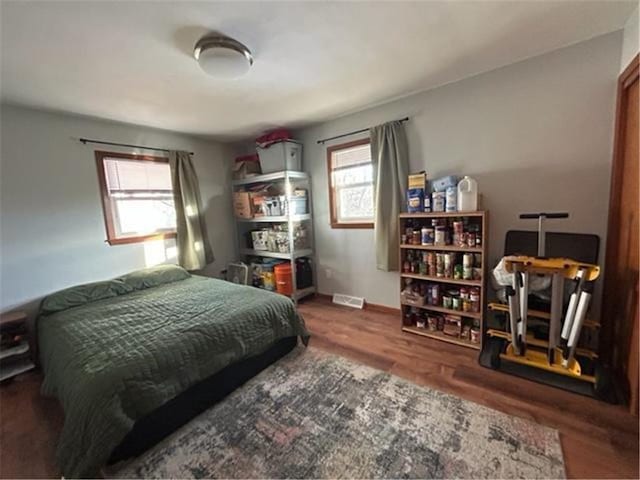 bedroom featuring multiple windows, dark wood finished floors, visible vents, and baseboards