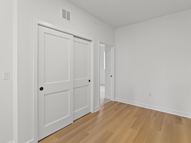 unfurnished bedroom with a closet and light wood-type flooring