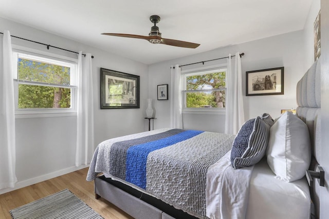 bedroom with ceiling fan, light hardwood / wood-style floors, and multiple windows