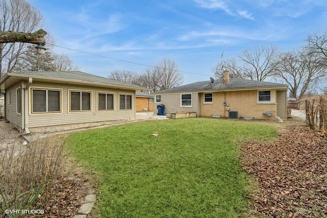 back of property with central AC and a lawn