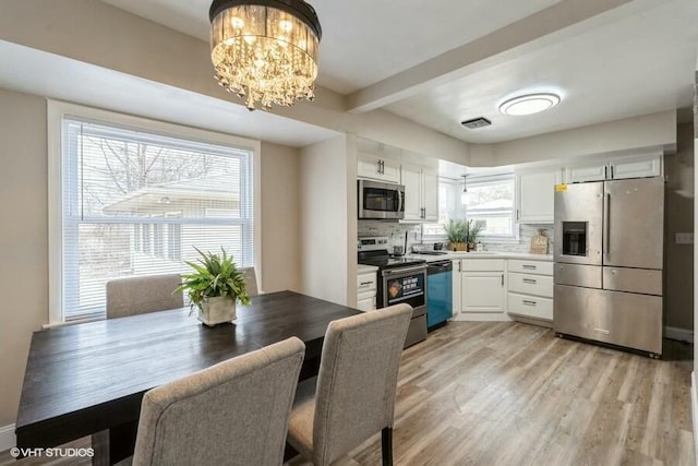 dining room with an inviting chandelier, beam ceiling, and light hardwood / wood-style flooring