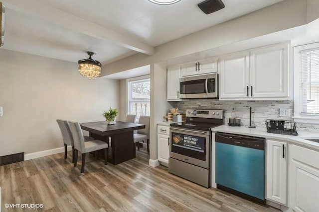 kitchen with tasteful backsplash, stainless steel appliances, light hardwood / wood-style floors, and white cabinets