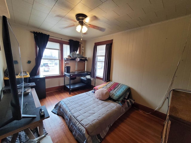 bedroom featuring ornamental molding, hardwood / wood-style floors, ceiling fan, and wood walls