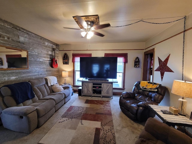 carpeted living room with ceiling fan and wood walls