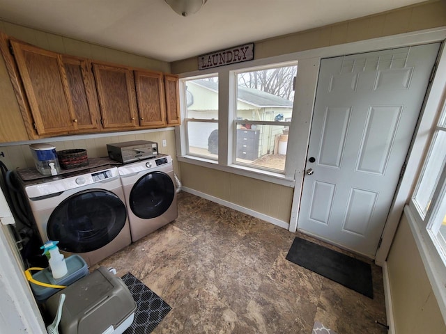 laundry room featuring cabinets, wooden walls, and washer and clothes dryer