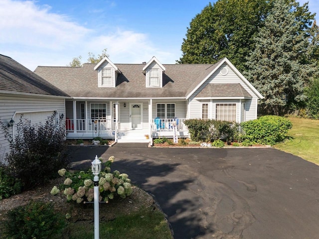 new england style home with covered porch and a garage